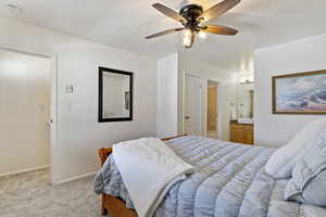 Bedroom featuring a closet, light colored carpet, ceiling fan, and ensuite bath