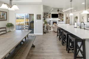 Dining room featuring sink, ceiling fan with notable chandelier, and wood-type flooring