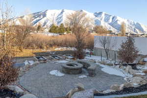 Snow covered patio featuring a mountain view and a fire pit