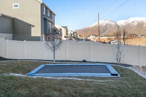 View of vehicle parking with a trampoline, a mountain view, and a lawn