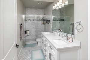 Bathroom with vanity, a shower with shower door, tile patterned floors, and toilet