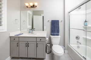 Full bathroom featuring tile patterned floors, vanity, toilet, and combined bath / shower with glass door