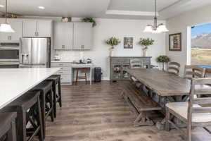 Dining space with a raised ceiling, a notable chandelier, and dark hardwood / wood-style flooring