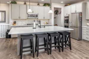 Kitchen featuring stainless steel appliances, hanging light fixtures, and a center island with sink