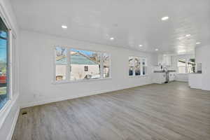 Unfurnished living room featuring sink and light wood-type flooring