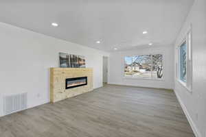 Unfurnished living room featuring a healthy amount of sunlight and light hardwood / wood-style flooring