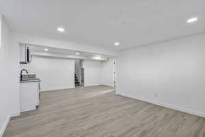 Unfurnished living room with sink and light hardwood / wood-style floors