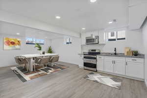 Kitchen featuring visible vents, baseboards, white cabinets, light wood-style floors, and appliances with stainless steel finishes