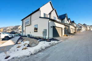 View of snowy exterior featuring cooling unit and a garage