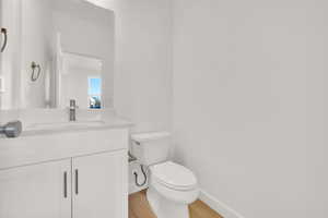 Bathroom featuring vanity, hardwood / wood-style flooring, and toilet