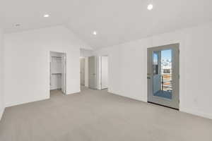 Unfurnished bedroom featuring lofted ceiling, access to outside, a walk in closet, light colored carpet, and a closet