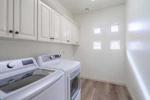 Laundry room featuring cabinets, washer and dryer, and light hardwood / wood-style floors