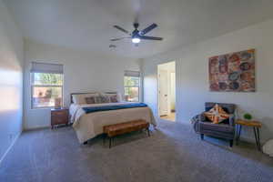 Bedroom featuring ensuite bath, ceiling fan, and carpet