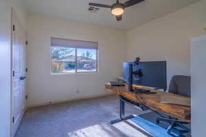 Carpeted office featuring ceiling fan