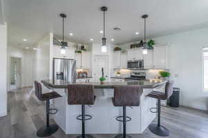 Kitchen with a large island, pendant lighting, a breakfast bar, appliances with stainless steel finishes, and white cabinets