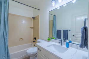 Full bathroom featuring vanity, shower / bath combination with curtain, and toilet