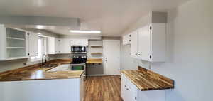 Main floor Kitchen with appliances with stainless steel finishes, butcher block countertops, and white cabinets