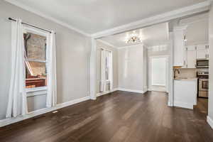 Interior space with crown molding, sink, and dark wood-type flooring