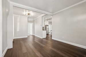 Empty room with dark hardwood / wood-style flooring and ornamental molding