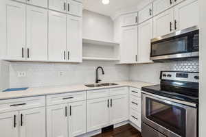 Kitchen featuring dark hardwood / wood-style floors, white cabinetry, sink, backsplash, and stainless steel appliances