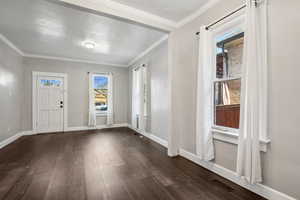 Entrance foyer with crown molding and dark hardwood / wood-style floors