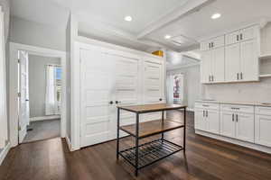 Kitchen featuring beamed ceiling, white cabinetry, dark hardwood / wood-style floors, and backsplash