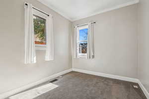 Carpeted empty room featuring ornamental molding