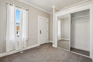 Unfurnished bedroom with crown molding, dark carpet, and a closet