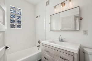 Full bathroom featuring tiled shower / bath combo, vanity, and toilet