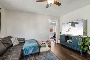 Living room featuring ceiling fan, dark hardwood / wood-style floors, and a textured ceiling