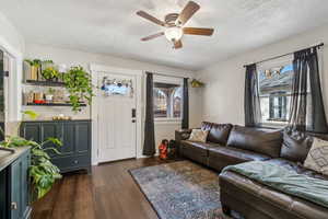 Living room featuring dark hardwood / wood-style flooring, ceiling fan, and a textured ceiling