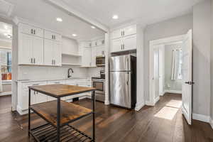 Kitchen featuring dark wood-type flooring, sink, white cabinetry, appliances with stainless steel finishes, and decorative backsplash