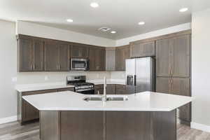 Kitchen featuring a kitchen island with sink, sink, light hardwood / wood-style flooring, and appliances with stainless steel finishes