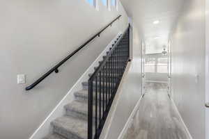 Stairs with hardwood / wood-style floors and ceiling fan