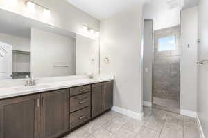 Bathroom with vanity, tile patterned flooring, and a tile shower