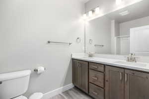 Bathroom with vanity, hardwood / wood-style flooring, a shower with shower door, and toilet