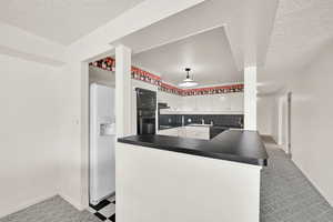 Kitchen with kitchen peninsula, white cabinets, a textured ceiling, and black appliances