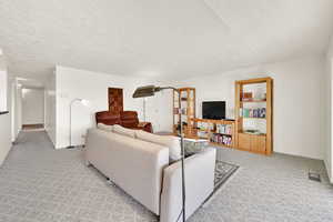 Living room with a textured ceiling and light carpet