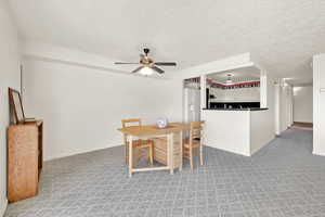 Carpeted dining room with ceiling fan and a textured ceiling