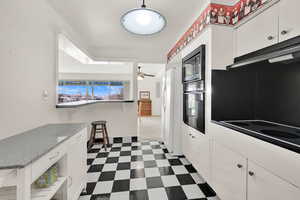 Kitchen featuring built in microwave, white refrigerator, white cabinetry, cooktop, and black oven