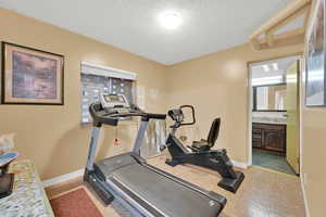 Exercise area with sink, a textured ceiling, and light tile patterned floors