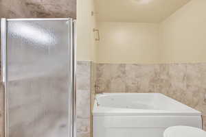 Bathroom featuring tile walls, a textured ceiling, and separate shower and tub