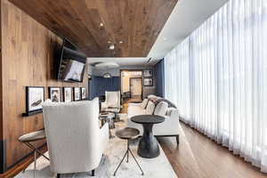 Living room with light wood-type flooring, wooden ceiling, and wood walls