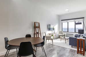 Dining room with light hardwood / wood-style floors and an AC wall unit