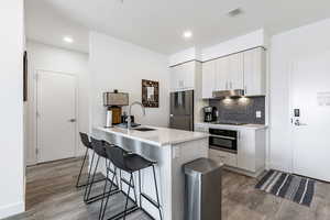 Kitchen featuring sink, backsplash, oven, stainless steel fridge, and light hardwood / wood-style floors