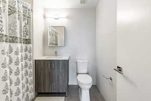 Bathroom featuring tile patterned flooring, vanity, tile walls, and toilet