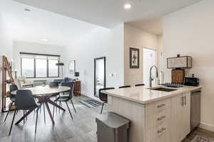 Kitchen featuring sink, light brown cabinets, light wood-type flooring, stainless steel dishwasher, and light stone countertops