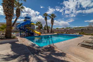 View of swimming pool featuring a water slide, a playground, and a patio