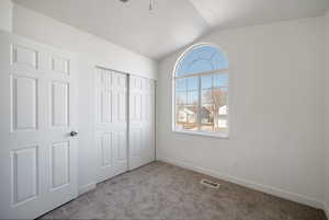 Unfurnished bedroom with lofted ceiling, light carpet, and a closet