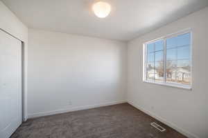 Unfurnished bedroom with a closet and dark colored carpet